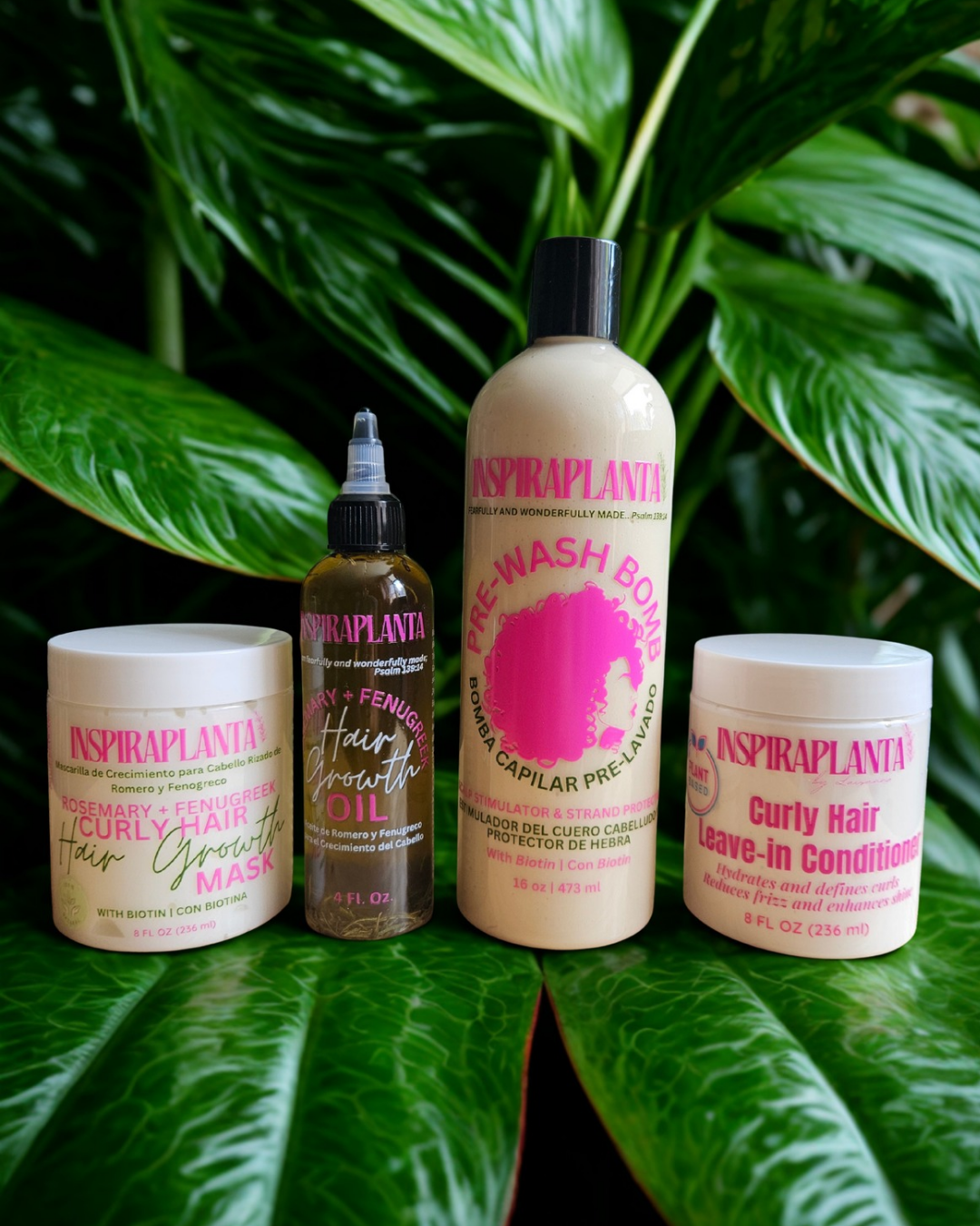 INSPIRAPLANTA 4-piece curly hair growth bundle including Pre-Wash Bomb, Hair Growth Mask, Growth Oil, and Leave-In Conditioner set on lush green leaves.